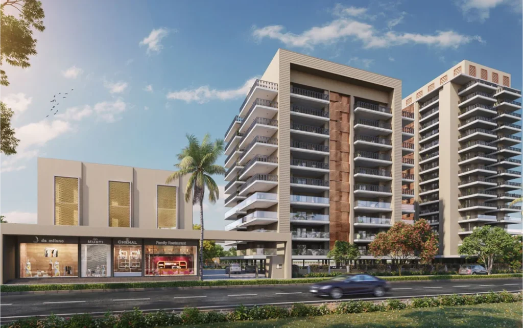 Modern luxury residential apartments with spacious balconies and a commercial shopping area in the foreground, located on a well-connected road with greenery and a clear blue sky.